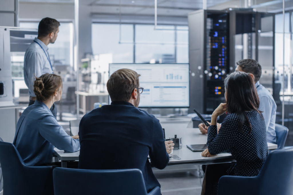 Équipe en entreprise analysant la continuité d’activité informatique avec vue d’ensemble sur postes de travail, infrastructure réseau et environnement technique multisite